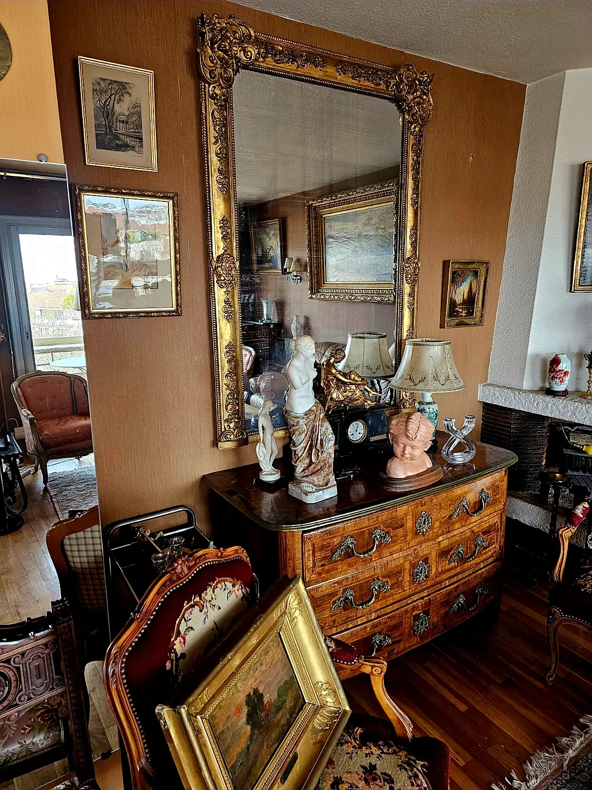 Salon avec commode en bois, miroirs et tableaux anciens