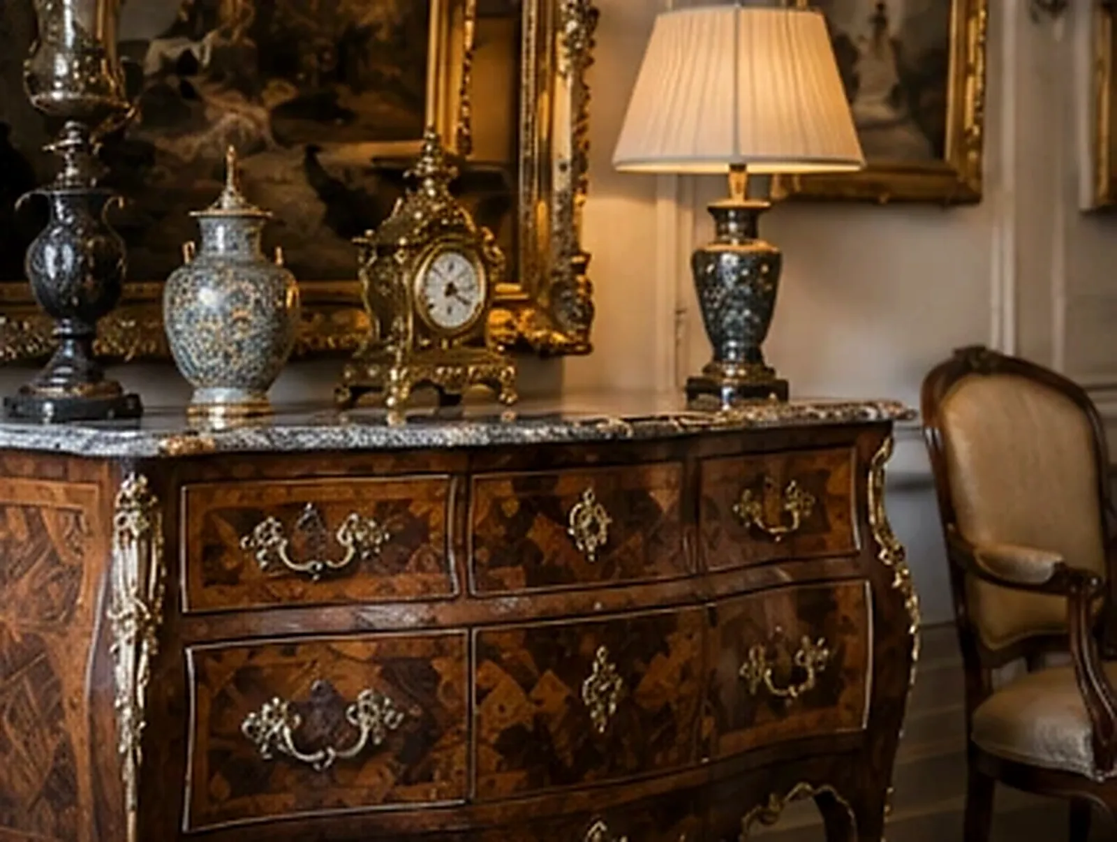 Commode galbée Louis XV en marqueterie avec bronzes dorés et plateau de marbre, ornée d'une pendule ancienne, de vases et d'une lampe, près d'un fauteuil d'époque