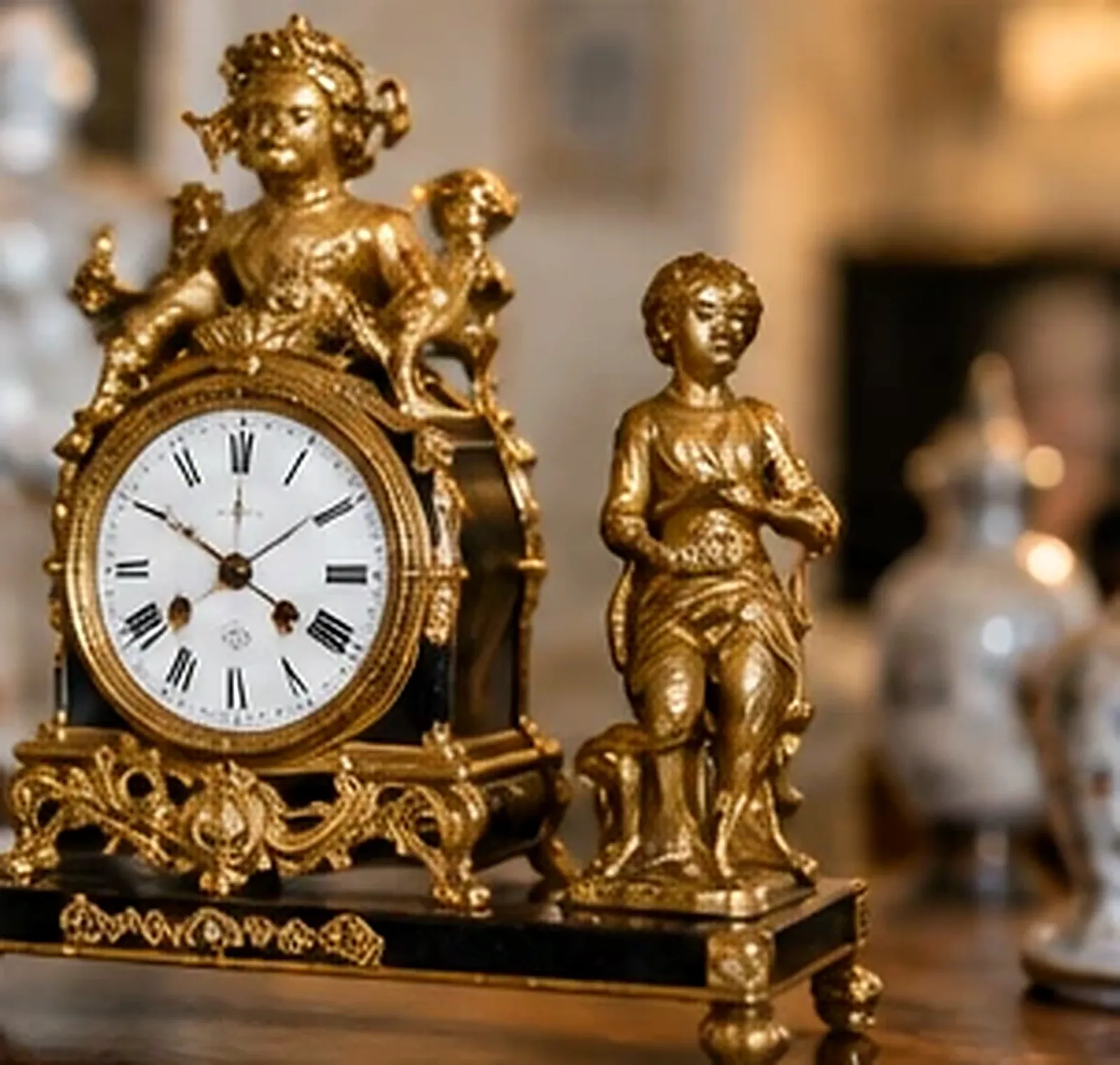 Pendule ancienne en bronze doré avec cadran blanc à chiffres romains et statuette de jeune garçon sur socle noir