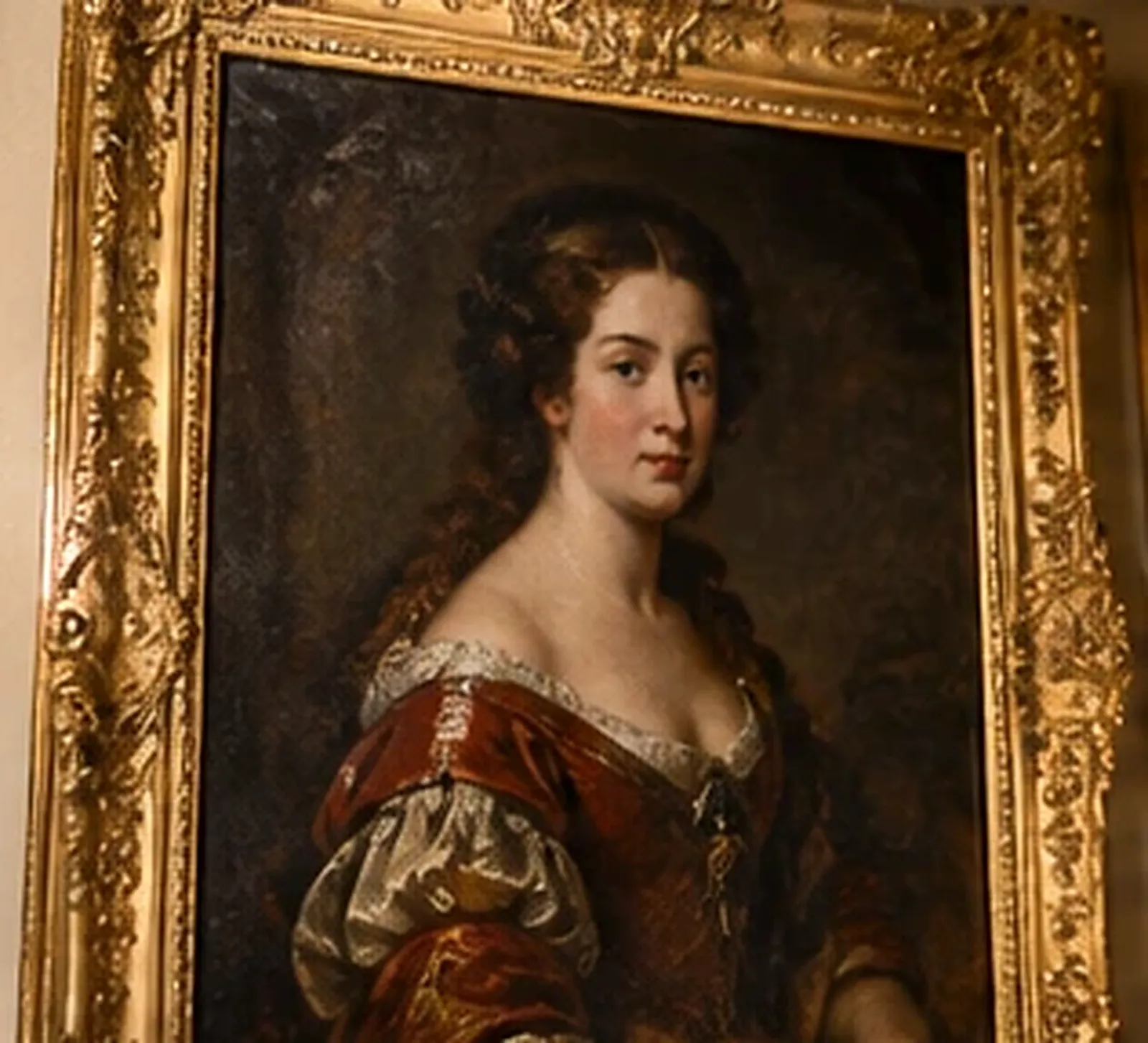 Portrait peint à l'huile d'une jeune femme en robe de velours rouge, dans un cadre doré richement sculpté
