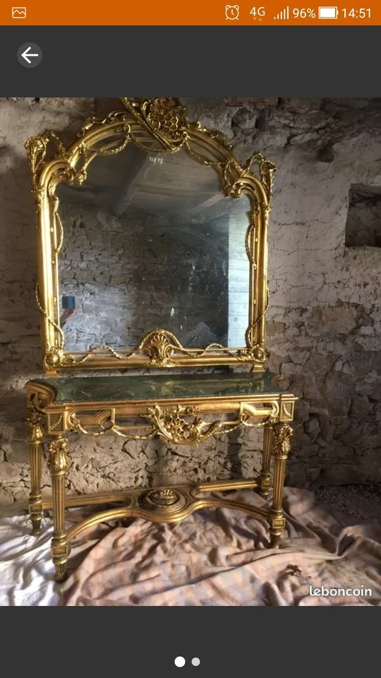 Miroir doré à fronton ajouré posé sur une console dorée à plateau de marbre